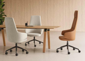 Dos sillones de oficina tapizados en gris claro y uno en marrón de respaldo alto alrededor de una mesa de reuniones de madera
