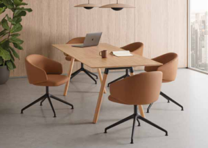 Cuatro sillones tapizados en marrón alrededor de una mesa de reuniones de madera junto a un ventanal
