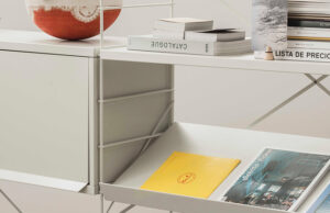 Detalle del estante blanco inclinado con revistas y del módulo de cajones