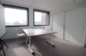 Sala de reuniones con mesa blanca plegable con ruedas y armarios empotrados