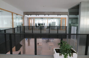 Vista desde el altillo con barandilla de chapa perforada hacia la sala de trabajo
