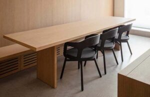 Mesa alargada de madera con sillas oscuras y banco corrido integrado en el revestimiento