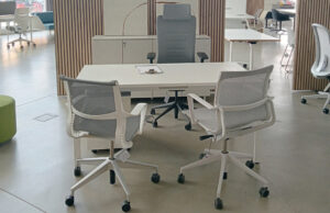 Mesa de despacho blanca con silla de dirección gris y dos sillas de malla blancas