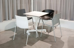 Mesa cuadrada blanca con cuatro sillas de distintos modelos y colores