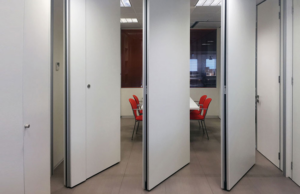 Tabiques móviles blancos abiertos dejando ver una sala de reuniones con sillas rojas