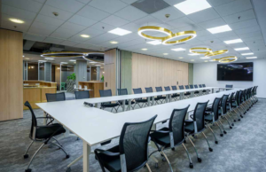 Sala de juntas amplia con mesa en U, tabique móvil de madera y pantalla