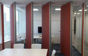 Tabiques móviles rojos dividiendo una sala en dos espacios de reunión