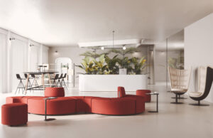 Vestíbulo con sofá modular curvo rojo, mostrador blanco y butacas huevo