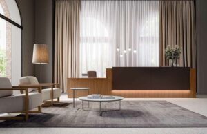 Recepción de hotel con mostrador de madera retroiluminado, butacas claras y cortinas