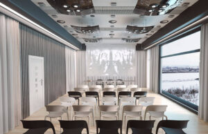 Sala de proyección con sillas apilables blancas y negras y ventanal panorámico