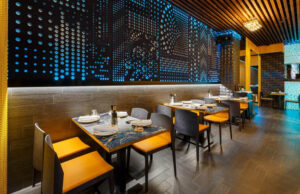 Restaurante con panel calado retroiluminado en azul y sillas naranjas
