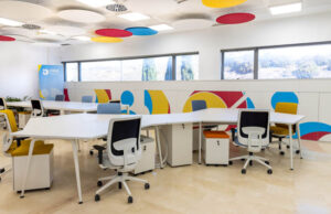 Oficina con plafones acústicos de colores en el techo y separadores impresos