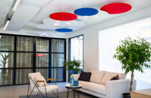 Recepción con plafones circulares rojos, azules y blancos, sofá y butaca