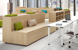 Gradas de madera con cojines de colores junto a mesas de trabajo blancas