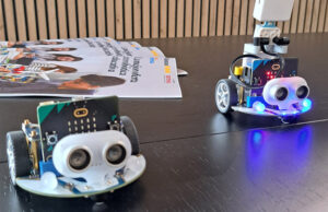Dos robots micro:bit con sensores de ultrasonidos y luces LED azules sobre la mesa