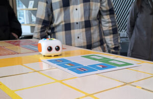 Docentes alrededor de una mesa con un robot y tarjetas de programación