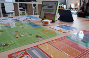 Robot educativo Matatalab sobre un tapete de actividades con tarjetas de programación y una tableta