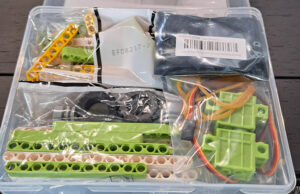 Bandeja con piezas de construcción verdes, motores y cableado del kit de robótica