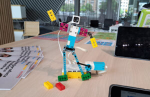 Robot construido con piezas LEGO Education y cámara, sobre una mesa con folletos de la jornada