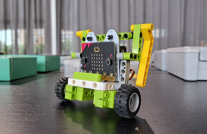 Robot con placa micro:bit montado sobre un chasis verde con ruedas