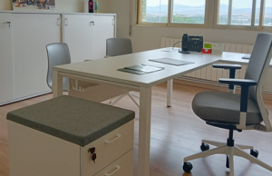 Mesa de trabajo blanca con cajonera con asiento tapizado y silla operativa gris