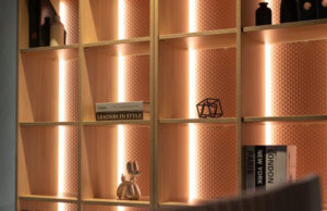 Detalle de estantería de madera con fondo terracota retroiluminado y objetos decorativos
