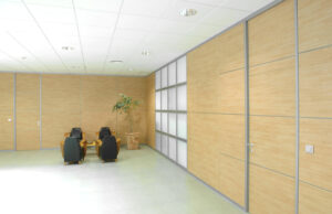 Sala de espera con mamparas de madera clara, paneles translúcidos y butacas