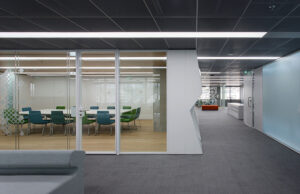 Sala de reuniones acristalada con sillas verdes y persianas venecianas integradas