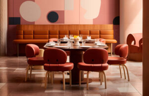Comedor con banco corrido, sillas rojas y mural acústico de formas geométricas