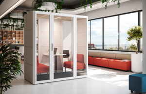 Cabina acristalada blanca con butacas rojas en una oficina con banco corrido y vistas
