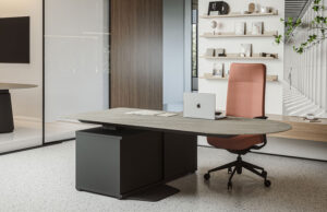 Mesa de dirección de tablero pétreo con silla ergonómica terracota y estanterías al fondo