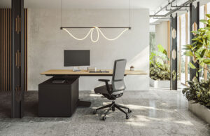 Puesto de trabajo con mesa elevable de madera, lámpara ondulada y vegetación