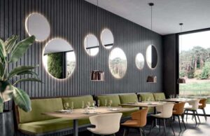 Restaurante con banco corrido verde, revestimiento de lamas oscuras y espejos circulares retroiluminados