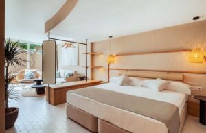 Habitación de hotel con cabecero tapizado, lámparas de fibra natural y terraza al fondo
