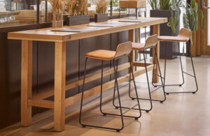 Barra alta de madera maciza con taburetes de asiento de cuero y estructura metálica negra