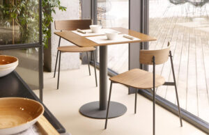 Mesa cuadrada de madera con dos sillas junto a un ventanal con vistas a la terraza